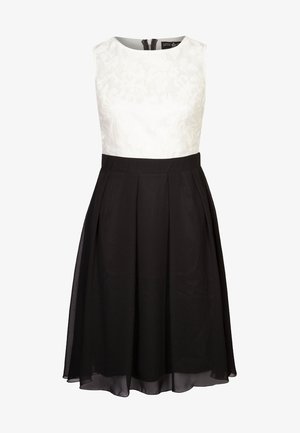 Sukienka bez rękawów z teksturowanym białym topem i czarną plisowaną spódnicą. Posiada okrągły dekolt i dyskretny zamek z tyłu.