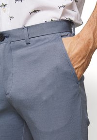 Modré kalhoty s texturou a síťovaným vzorem, s rovnými předními díly, bočními kapsami a zapínáním na knoflík.