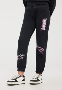 Pantaloni sportivi neri con polsini elasticizzati, caratterizzati da testi grafici colorati: "BEST", "AWESOME LOVE" e "FRIENDS FOREVER". Realizzati in materiale morbido.