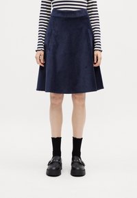 Marinblå kordflod A-linjeformad kjol med ribbad midja och sidofickor, ihopparad med svarta platåskor och ribbade svarta strumpor. Randig topp i sikte.