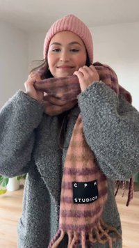 Zachte sjaal van een wolmix in tinten roze en bruin met geruit patroon, franjes aan de randen en een zwart label met het merk "CPH STUDIOS".