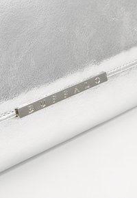 Närbild av en silverfärgad texturerad yta med en horisontell metallskylta graverad med ordet "BUFFALO."