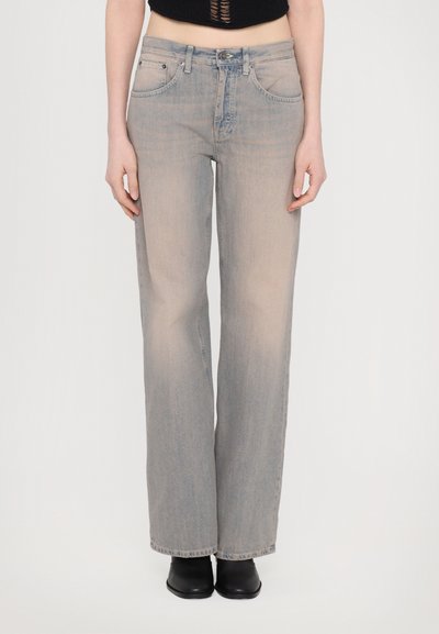 Jean large gris clair en denim doux, présentant une taille haute, un design classique à cinq poches et une légère décoloration. Associé à des bottes noires.