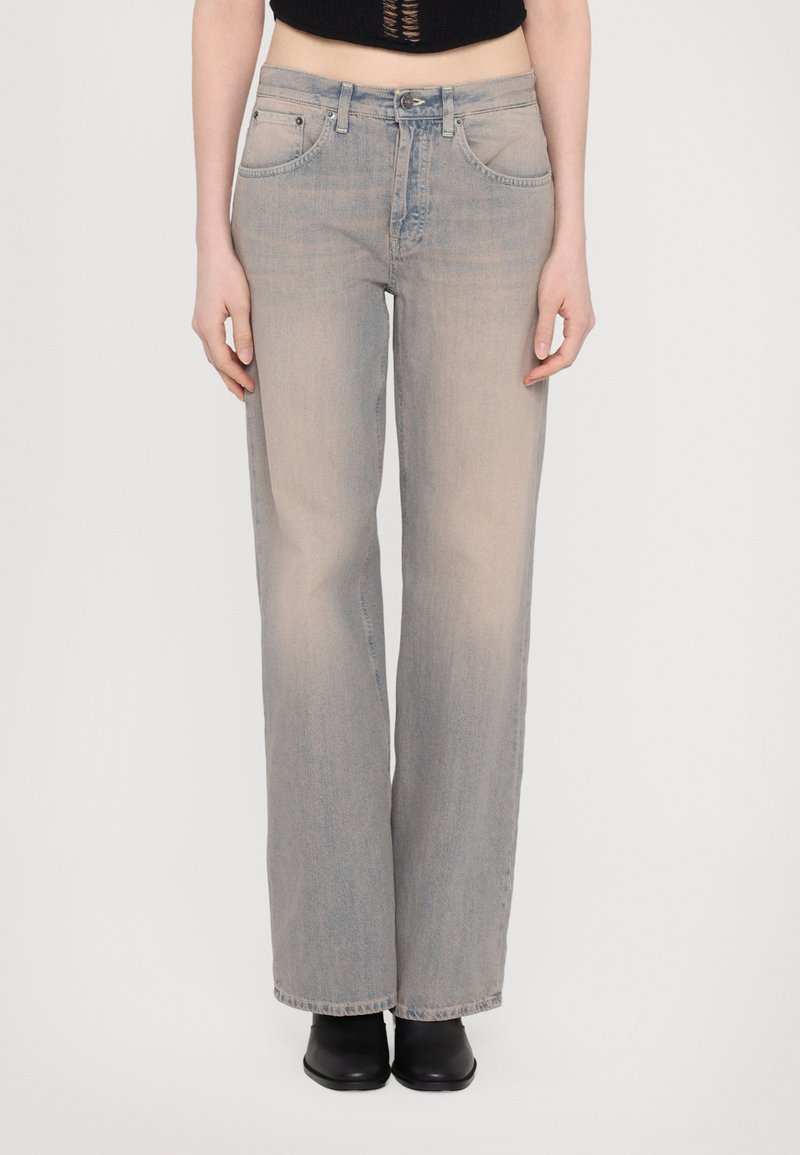 Jeans de perna larga cinza claro em denim macio, com uma cintura alta, design clássico de cinco bolsos e um leve desbotado. Combinados com botas pretas.