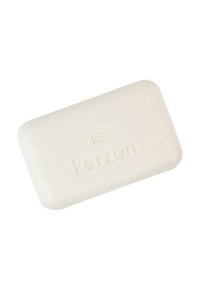 Cremfarbige Seife mit abgerundeten Kanten, versehen mit einem eingestanzten Logo. Glatte Textur mit einem subtilen Schimmer.