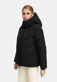 Musthave mustajast puffer-jakkide, millel on kõrge krae ja reguleeritav kapuuts. Omab tikitud mustrit ja kahte lukuga küljetaskut, valmistatud soe materjal.