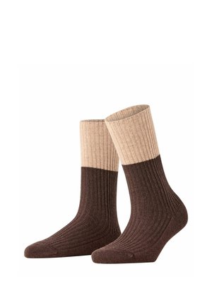 Paar gerippte zweifarbige Socken mit dunkelbraunem Fuß und Unterbein sowie beigem Oberschenkel, auf weißem Hintergrund aufrecht dargestellt.