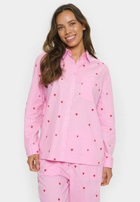 Camicia rosa a maniche lunghe con taschino e un motivo di piccoli cuori rossi distribuiti uniformemente sul tessuto.