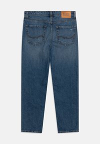 Denimjeans i mörkblått med en urblekt effekt, med medelhög midja, fyra fickor och en tan läderlogotyp på baksidan.