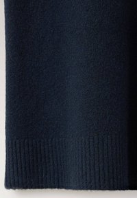 Tissu en laine bleu marine foncé avec un détail de bord-côte en bas, montrant la texture et le motif tricoté.