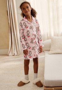 Pink pajama set featuring a bunny pattern with festive accents. The fabric is soft, long-sleeved, with button closure and two front pockets.