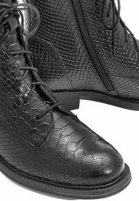 Czarne skórzane botki za kostkę z wytłaczanym wzorem węża, z sznurowaniem z przodu, zamkiem błyskawicznym z boku, okrągłym noskiem oraz płaską gumową podeszwą.