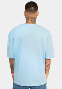 Lyseblå oversized t-shirt i bomuld med korte ærmer og rund halsudskæring. Glat tekstur, uden synlige mønstre eller grafik.