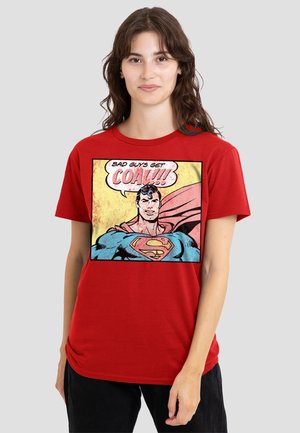 Young woman wearing a red t-shirt with a comic-style Superman graphic and text "Bad guys get caught" on the front.