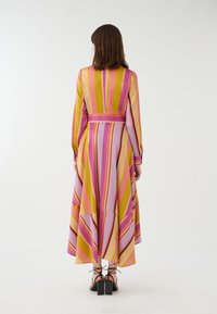 Gestreiftes Kleid in mehreren Farben mit vertikalen Linien in Pink, Lila und Gelb. Lange Ärmel, tailliert und mit fließendem Saum.