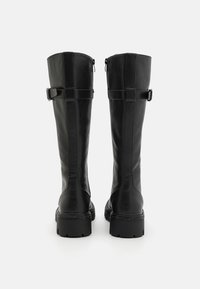 Bottes hautes jusqu'aux genoux en cuir noir à finition lisse, avec un détail de boucle à l'arrière et une semelle à crampons épaisse pour une meilleure adhérence.