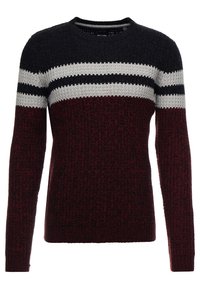 Pull en maille avec un col rond, présentant des rayures bordeaux, bleu marine et blanches. Texture épaisse avec des bandes de couleurs contrastantes sur la poitrine.