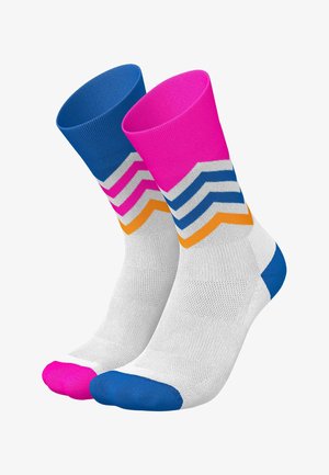 Paar weiße Crew-Socken mit bunten Chevron-Streifen, ein Socken mit pinkem Bündchen und Spitze, der andere mit blauem Bündchen und Spitze.