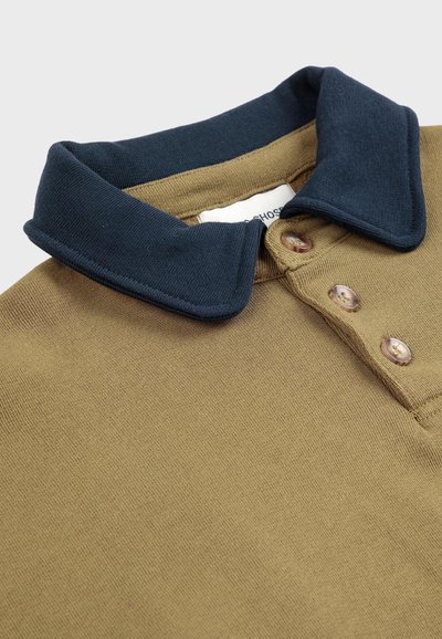 Polo shirt olive vert avec un col bleu marine. Patte de boutonnage à trois boutons avec des boutons marron clair. Tissu doux et texturé.