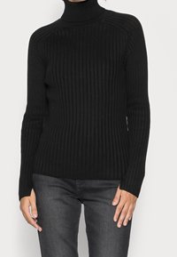 Schwarzer, gerippter Rollkragenpullover mit langen Ärmeln, aus gestricktem Stoff gefertigt. Figurbetontes Design mit einem strukturierten Muster auf der Oberfläche.