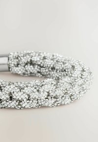 Silberne geflochtene Haarband, bedeckt mit kleinen, funkelnden Strasssteinen, mit einem glänzenden Metallverschluss, der eine strukturierte Oberfläche und ein filigranes Design aufweist.