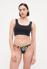 Black cropped bikini top with wide straps, paired with low-rise bikini bottoms featuring a colorful floral pattern on a dark background.