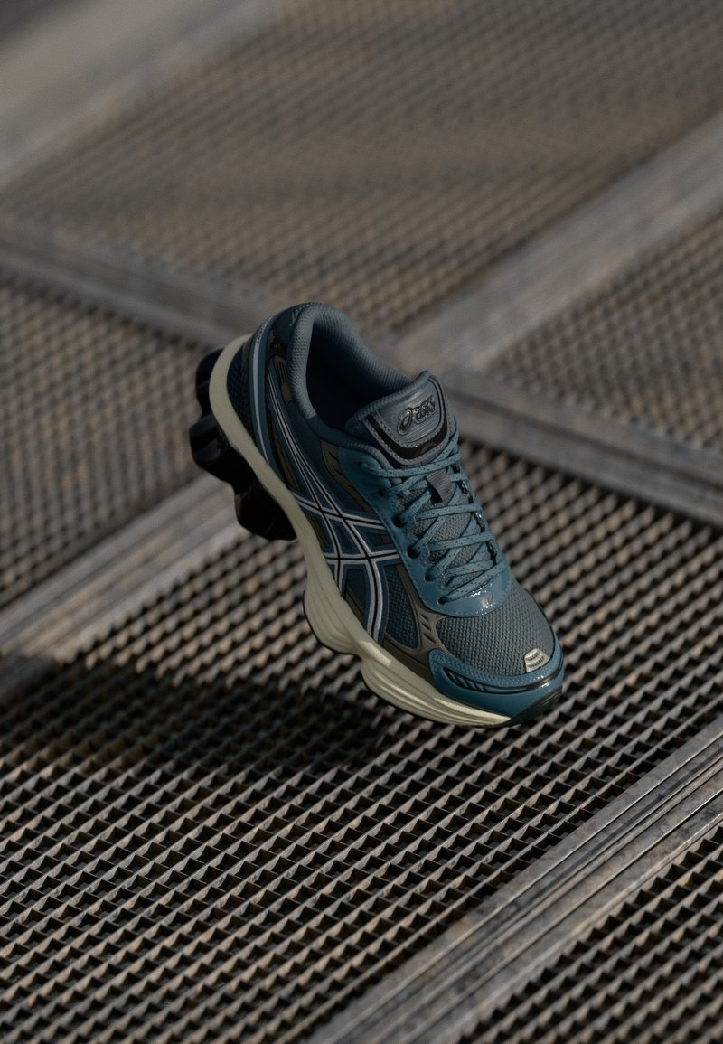 Chaussure de course pour homme avec un dessus en mesh bleu foncé, des accents noirs, une semelle épaisse couleur crème et un design de semelle distinctif pour l'adhérence.