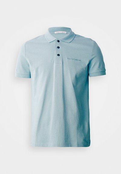 Svetlo modra polo majica z mehkim bombažnim materialom, tremi črnimi gumbi in izvezenim logotipom na prsih. Kratke rokave in klasičen ovratnik.