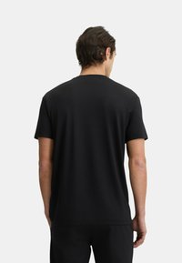 T-shirt nera a maniche corte con collo tondo, realizzata in tessuto morbido, con taglio dritto e design minimalista, senza modelli o accenti visibili.