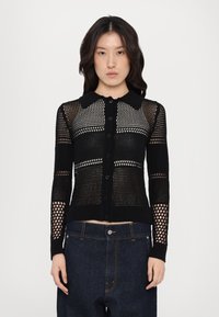 Black knit cardigan featuring a button-front design, detailed with mesh patterns and a classic collar. Textured sleeves and hem.