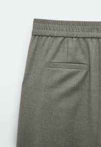 Pantalon avec ceinture élastique grise et une poche passepoilée arrière, fabriqué en tissu doux de poids moyen.