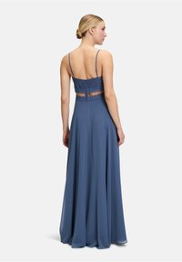 Robe longue bleue avec un dos en dentelle, fines bretelles, jupe fluide et texture lisse, conçue pour des occasions formelles.