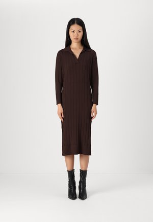 Brown ribbed dress with a collar and long sleeves, reaching mid-calf. Worn with fitted black ankle boots. Plain white background.