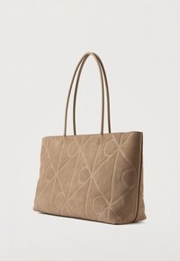 Beige velúr bevásárlótáska geometrikus mintázattal és sima felülettel, két hosszú fogantyúval és struktúrált, téglalap alakú formával.