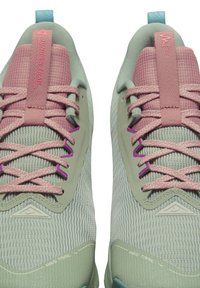 Trailsko til løb med en lys grøn mesh-overdel, pink snørebånd og lilla detaljer. Har en grå tekstureret mellemsål og logodetaljer.