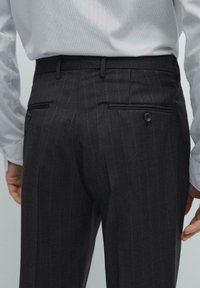 Dark gray pinstriped trousers with a smooth texture, featuring two back pockets with buttons and a fitted waistband.