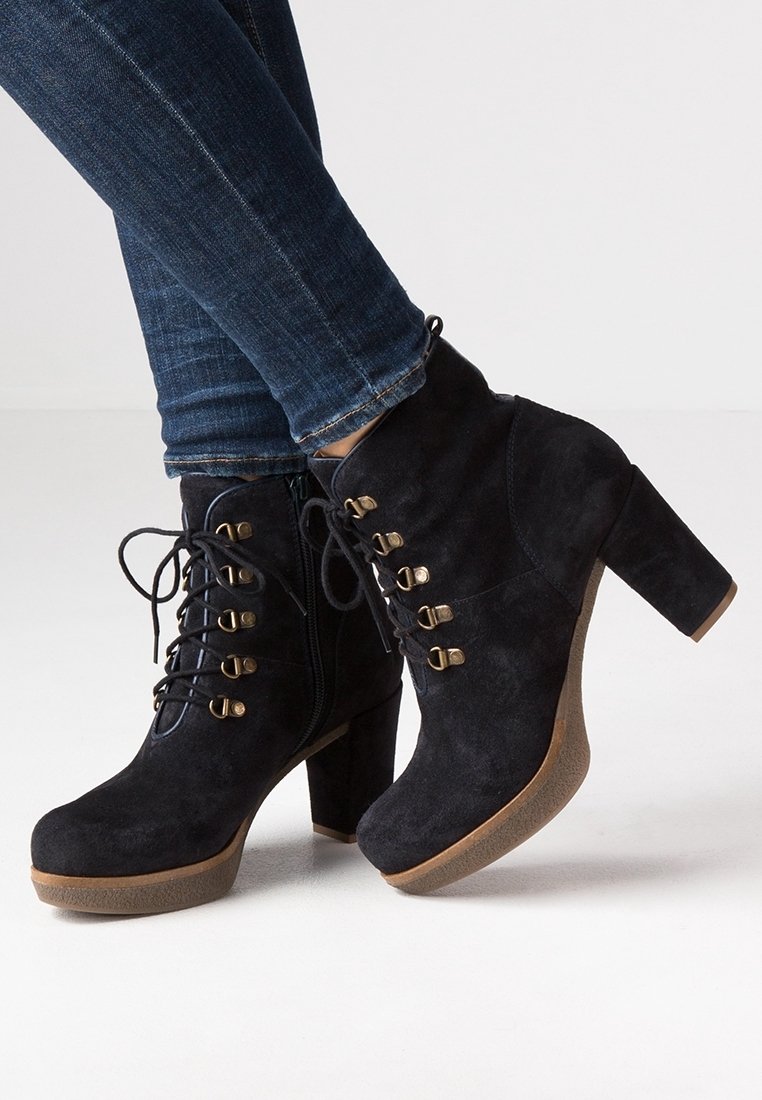 Czarne zamszowe botki za kostkę na grubym obcasie, z ozdobnymi złotymi oczkami, sznurowadłami oraz bocznym zamkiem błyskawicznym dla łatwego zakładania.