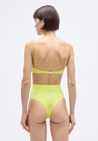 Augsta vidukļa bikini komplekts spilgti dzeltenā krāsā, ar plānām siksnām un aizdari aizmugurē, izgatavots no gluda materiāla ar minimālu dizainu.