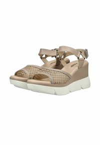 Sandales compensées beiges avec semelles blanches épaisses, brides à la cheville et bouts ouverts présentant un design en maille tissée.