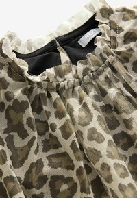 Hedvábná blůza s leopardím vzorem vyrobená z průhledné látky. Má zvlněný výstřih a elastické nabírání, s černou podšívkou.