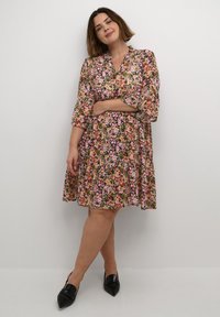 Robe fleurie avec un motif multicolore de rose, jaune et vert, dotée d'un col et de manches trois-quarts.
