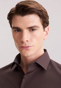 Bruine overhemd met een button-down kraag, voorzien van een gestreepte binnenkraag. Gladde textuur, slim fit ontwerp en geen zichtbare logo's.