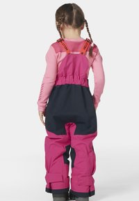 Růžový a námořnický voděodolný snowsuit s nastavitelnými popruhy, elastickým pasem a zesílenými koleny, navržený pro trvanlivost v chladném počasí.