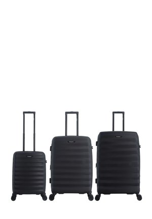 Drei schwarze Hartschalenkoffer in kleinen, mittleren und großen Größen mit ausgezogenen Griffen und jeweils vier Rollen, nebeneinander stehend.
