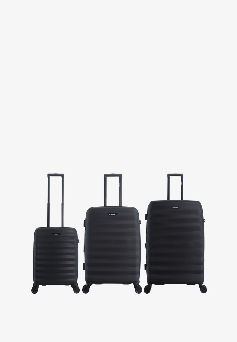 Three black hard-shell suitcases of small, medium, and large sizes with extended handles and four wheels each, standing side by side.