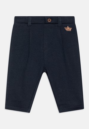 Pantalones para niño pequeño en azul marino con cierre de botón, trabillas para cinturón y un pequeño barco de papel bordado en marrón en la parte superior derecha.