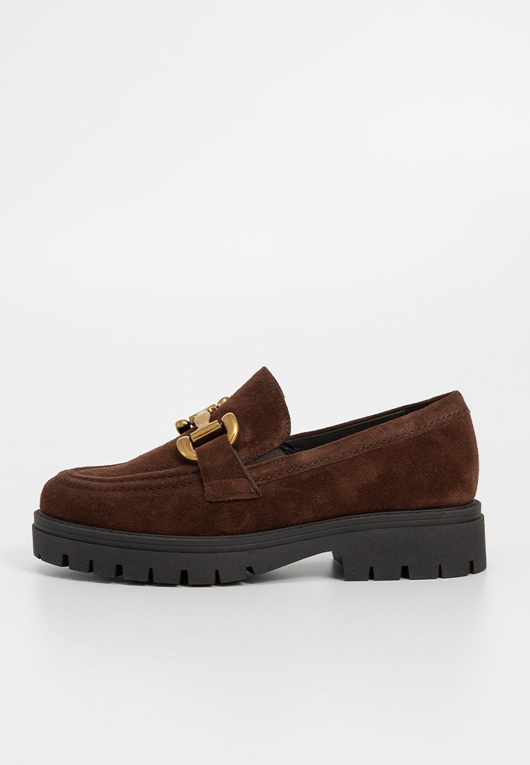 Bruine suède leren loafers met een chunky zwarte rubberen zool, voorzien van een decoratieve gouden gespdetail aan de voorkant en gestikte accenten.