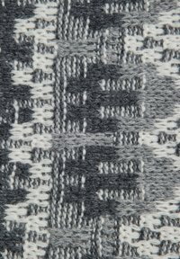 Primo piano di un tessuto a maglia texturizzato con filati grigi, grigio scuro e bianchi che formano motivi geometrici e lineari.