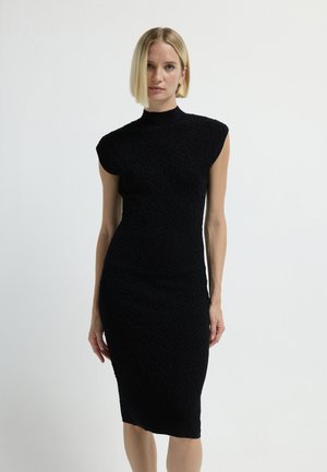 Abito nero a maglia con silhouette aderente, collo a barchetta e maniche corte a campana. La trama presenta un delicato design a motivi in tutto l'abito.