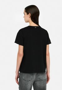 Schwarzes Baumwoll-T-Shirt mit kurzen Ärmeln, lässiger Passform und rundem Ausschnitt. Hat ein kleines Logo am Hinterhals.